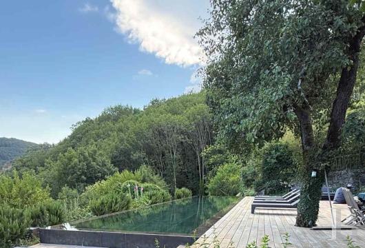 Dans le parc naturel des Grands Causses, un hameau dominant le paysage avec ses maisons, son jardin et sa piscine ceints de 7 ha de bois 